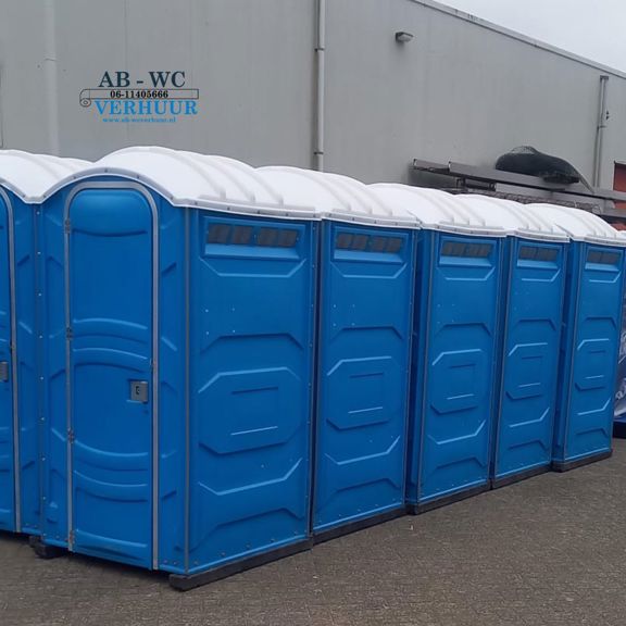 Rij blauwe mobiele toiletten van AB-WC Verhuur bij een bedrijfspand