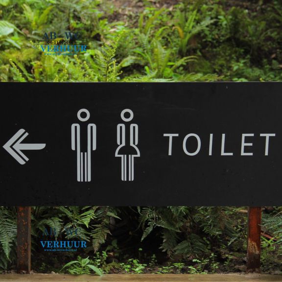 Zwart bord met pijl, pictogrammen en de tekst TOILET tussen varens